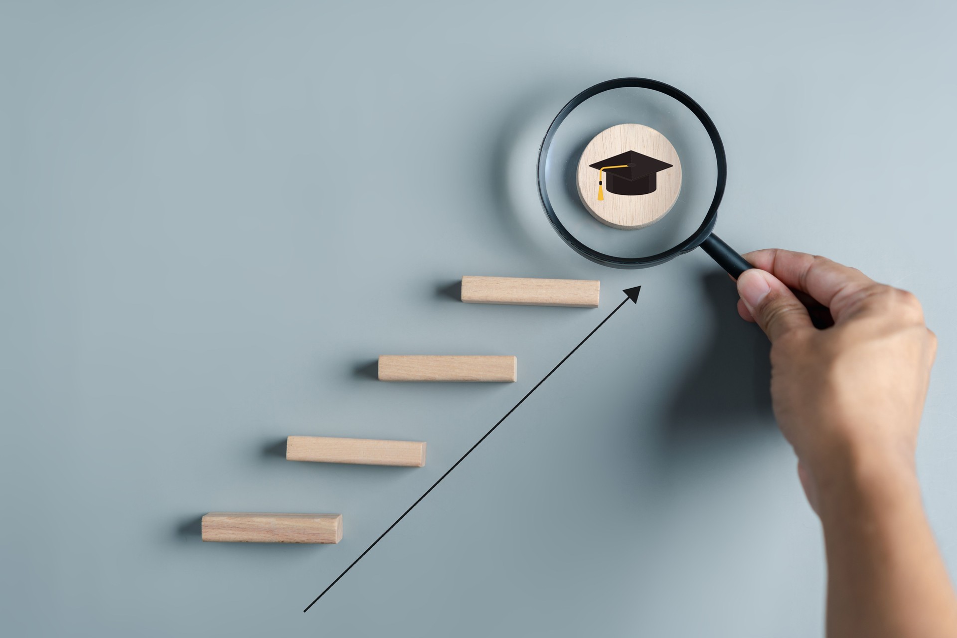 Steps of education leading to success goal. Taking strategic steps towards graduation. Career path and first for business, Graduation achievement goals concept. Graduation cap on wooden block.